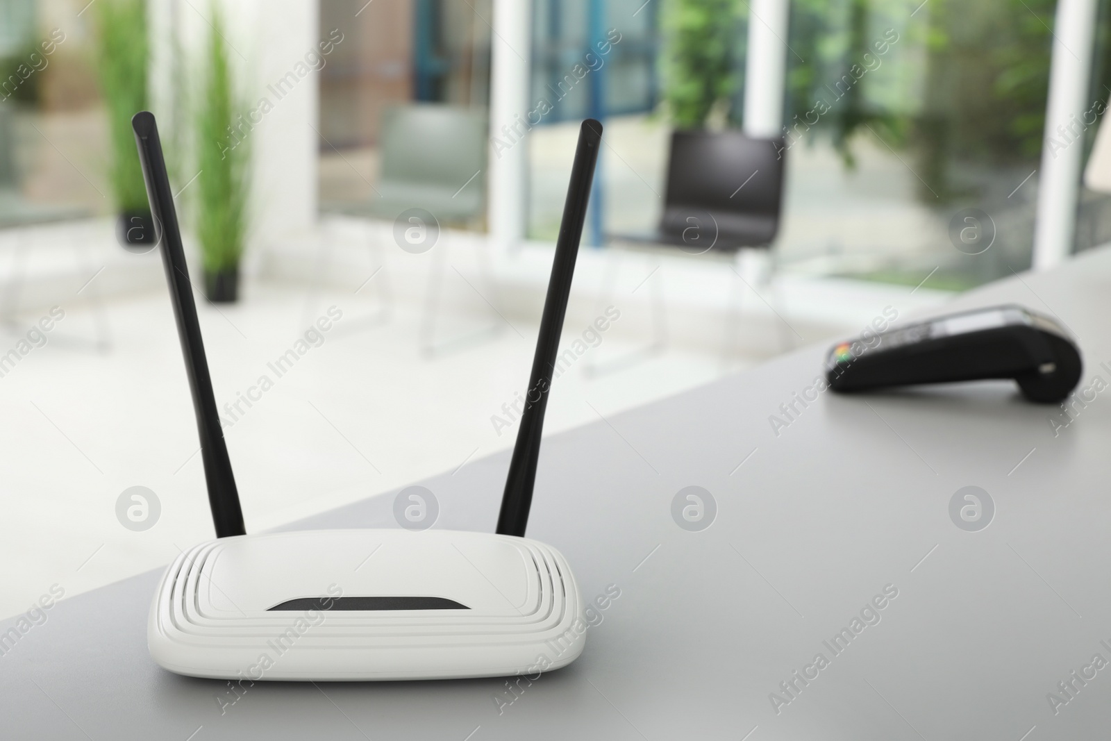 Photo of Modern Wi-Fi router on grey table indoors, space for text