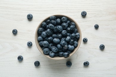 Photo of Ceramic bowl with blueberries on white wooden table, flat lay. Cooking utensil