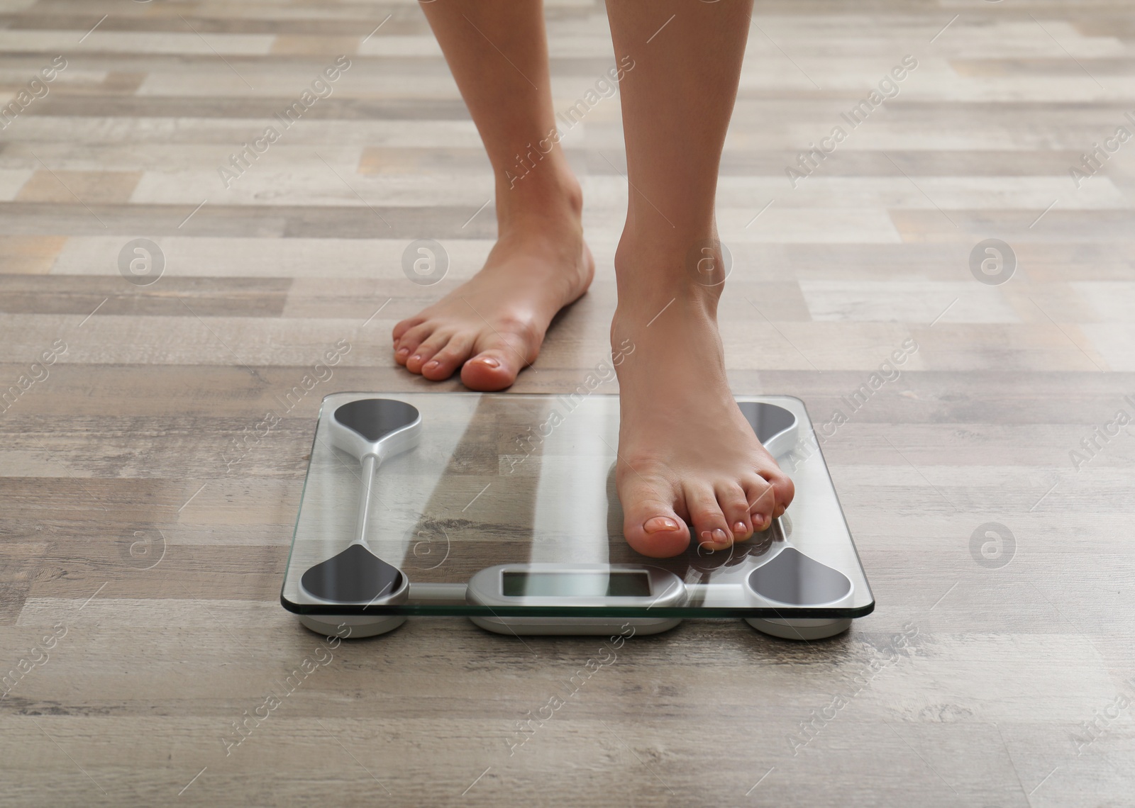 Photo of Woman stepping on floor scales indoors, closeup. Weight control