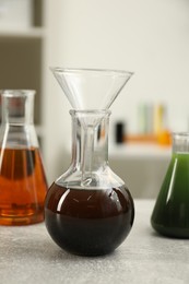 Laboratory glassware with different types of crude oil on light grey table