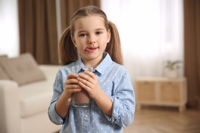 Cute little child with glass of tasty chocolate milk at home