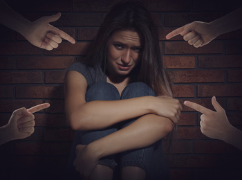 People bullying young woman near brick wall