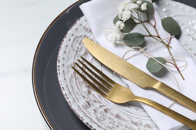 Stylish cutlery, flower and eucalyptus leaves on white background, closeup