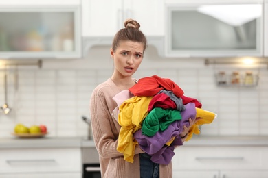 Photo of Woman holding pile of dirty laundry in kitchen