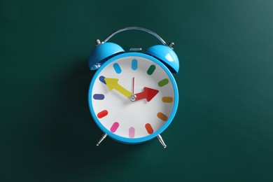 Alarm clock on green background, top view. School time