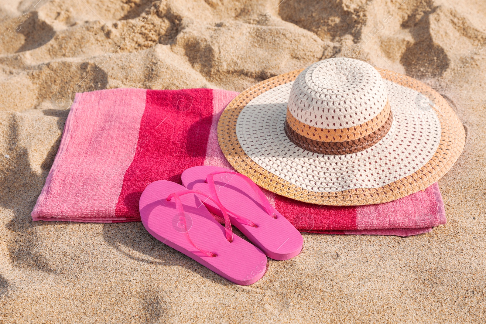 Photo of Beach towel with straw hat and slippers on sand