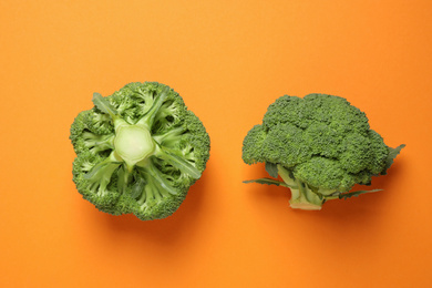 Photo of Fresh tasty broccoli on orange background, flat lay