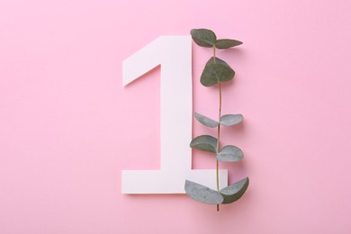 Photo of Paper number 1 and eucalyptus branch on pink background, flat lay