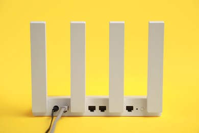 Photo of One modern Wi-Fi router on yellow background