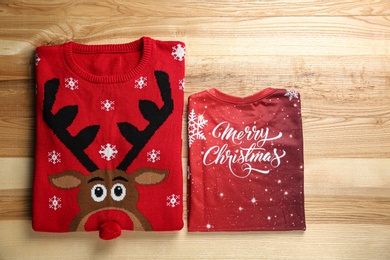 Folded warm Christmas sweaters on wooden table, flat lay