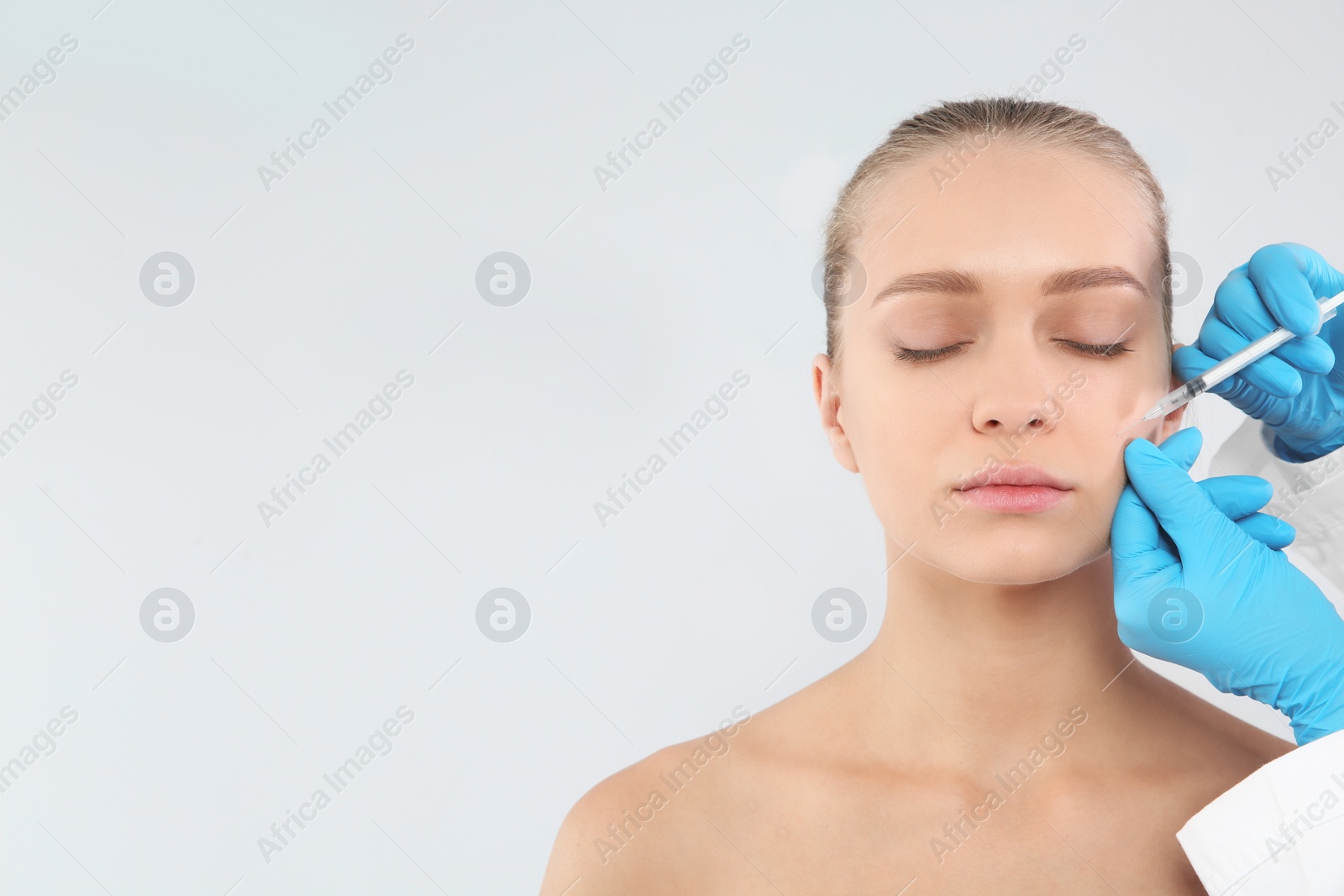 Photo of Young woman getting facial injection and space for text on white background. Cosmetic surgery concept
