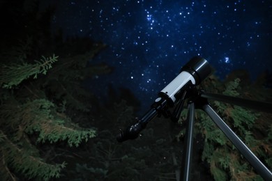 Modern telescope at night outdoors, low angle view. Learning astronomy