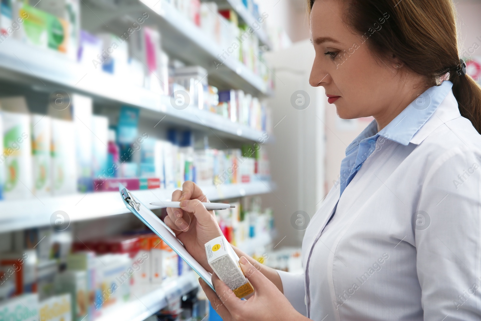 Photo of Professional pharmacist near shelves with merchandise in modern drugstore