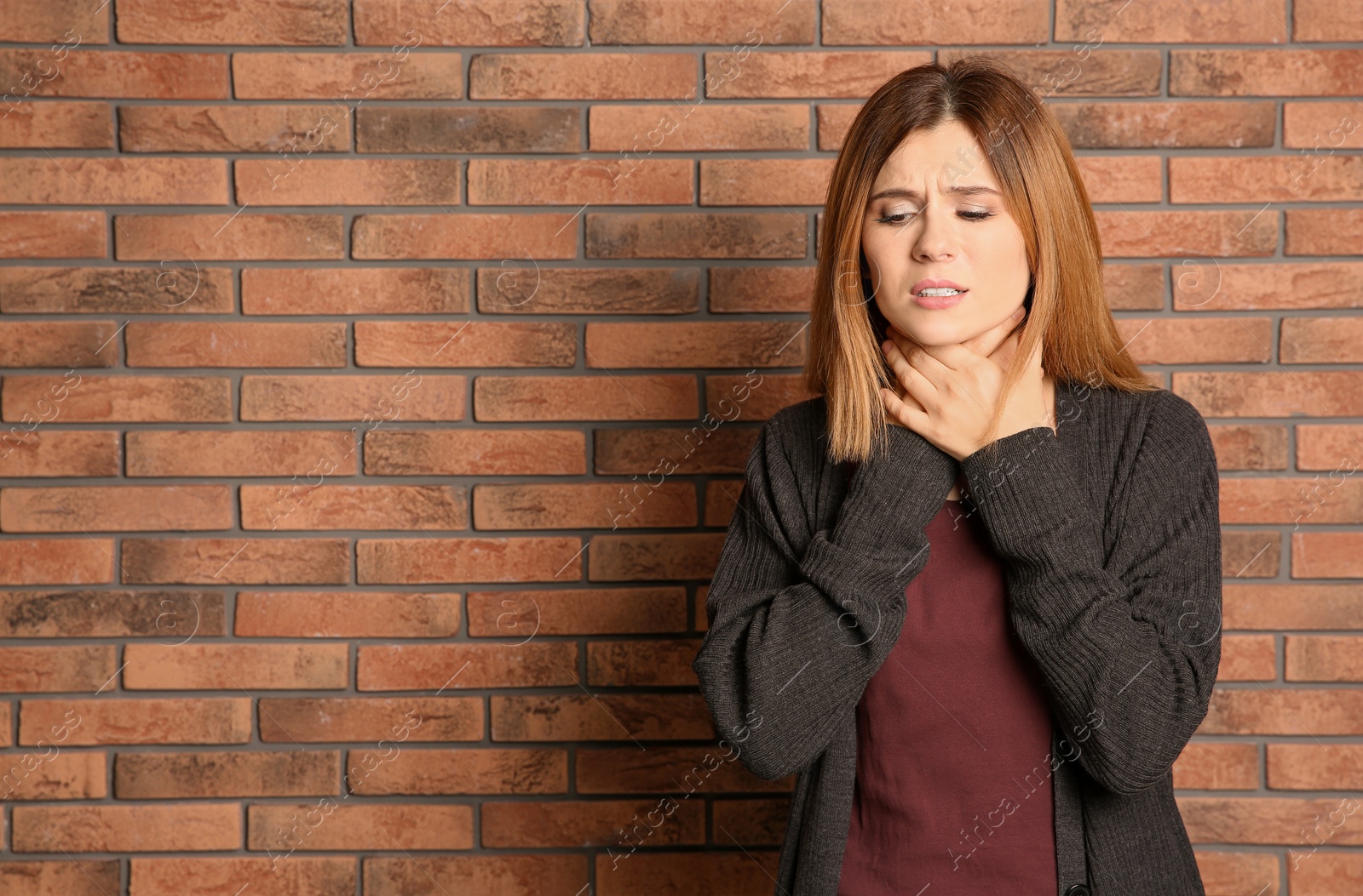 Photo of Woman suffering from cough near brick wall. Space for text