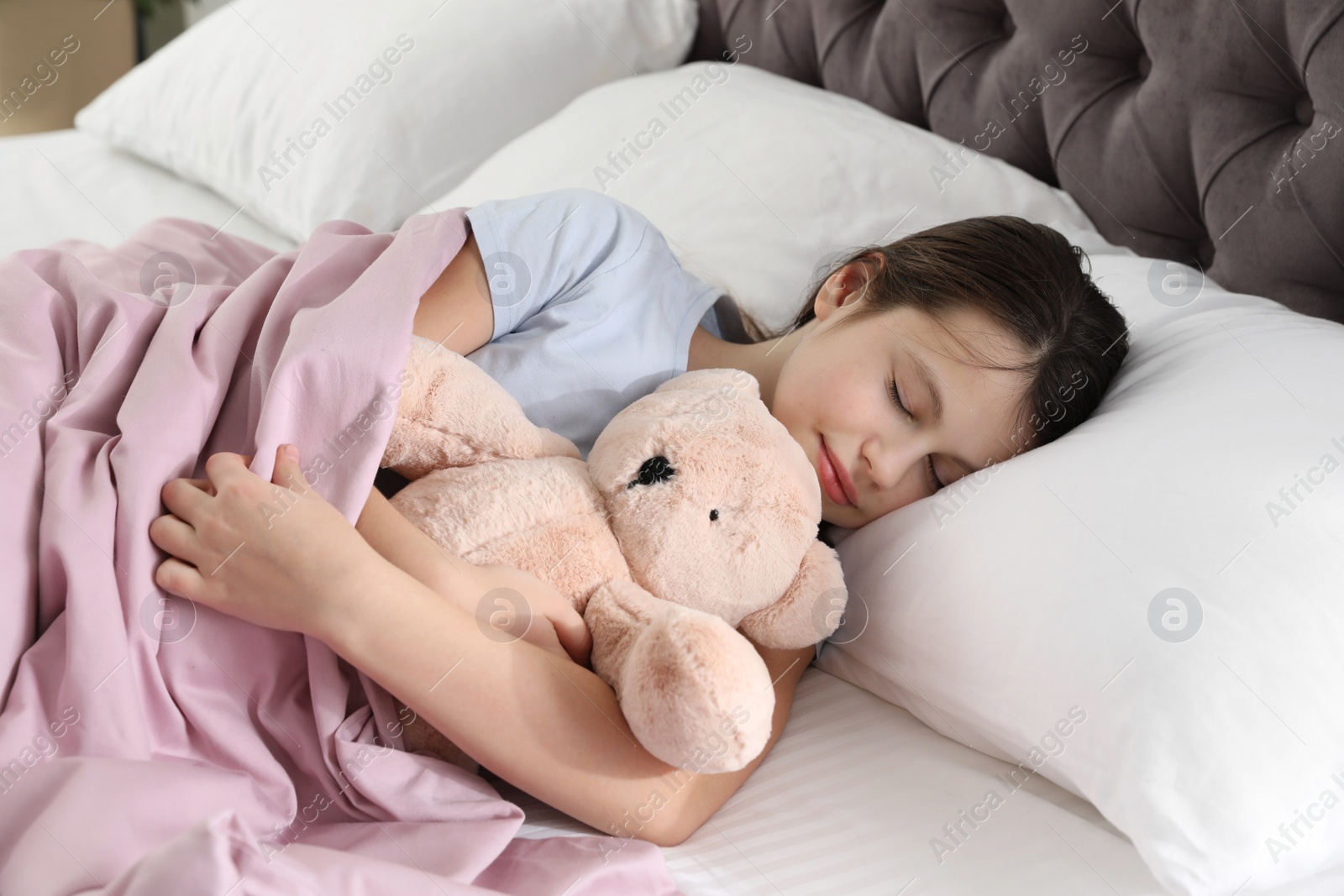 Photo of Beautiful little girl with teddy bear sleeping in bed