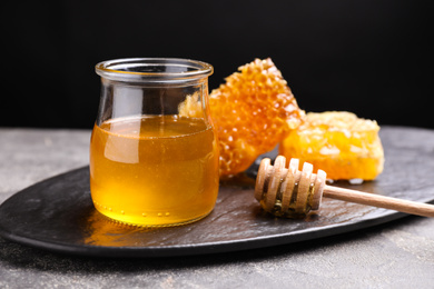 Photo of Tasty aromatic honey and combs on grey table