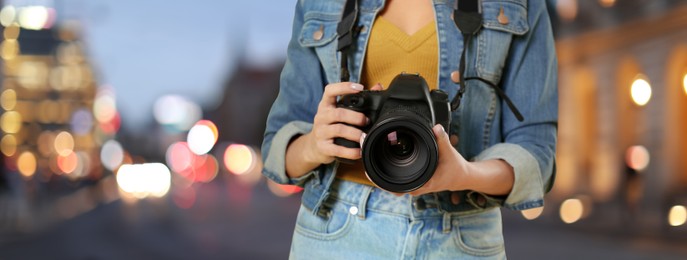 Professional photographer with modern camera and blurred view of beautiful city in evening. Banner design