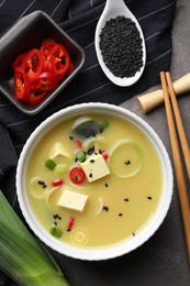 Photo of Bowl of delicious miso soup with tofu served on grey table, flat lay