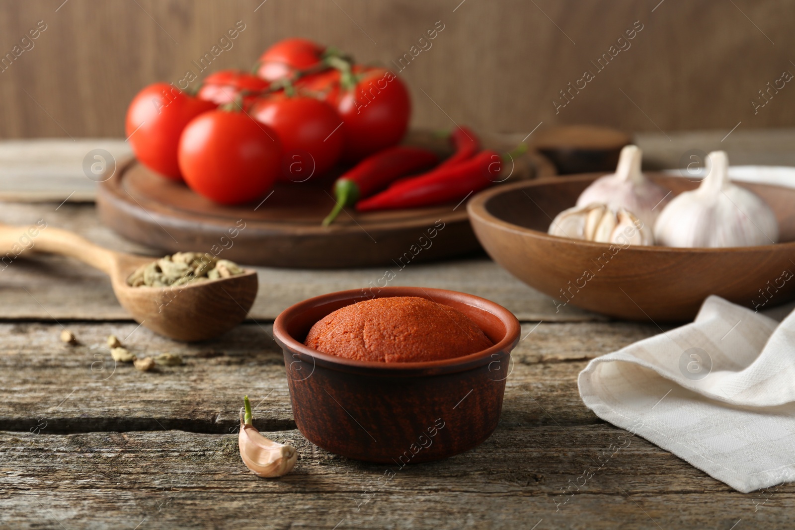 Photo of Red curry paste in bowl and ingredients on wooden table