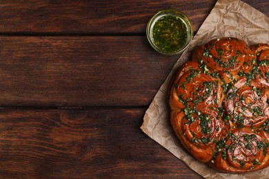 Traditional Ukrainian garlic bread with herbs (Pampushky) and aromatic oil on wooden table, flat lay. Space for text