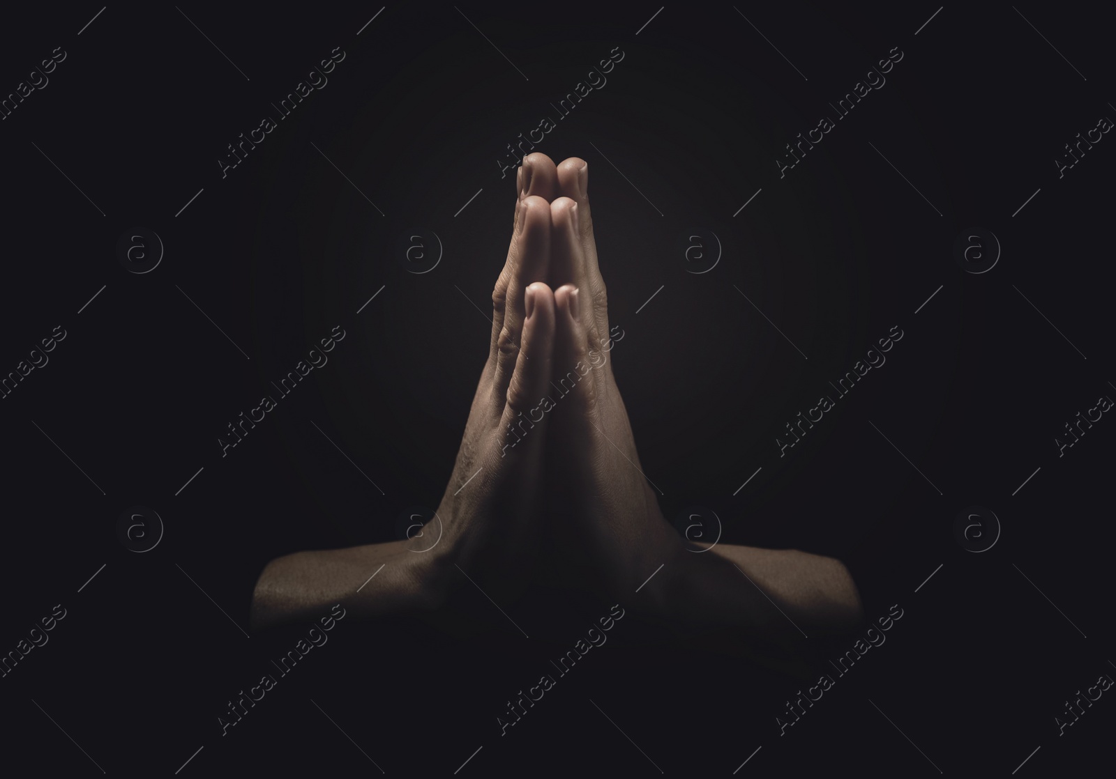 Image of Christian woman praying in darkness, closeup. Belief