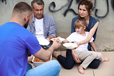 Poor people receiving food from volunteer outdoors