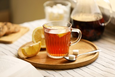 Photo of Glass mug of aromatic tea with lemon and sugar on table