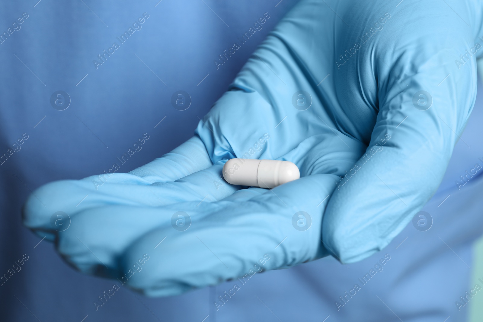 Photo of Doctor in medical glove holding pill, closeup view