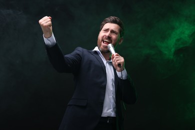 Photo of Emotional man with microphone singing in color light