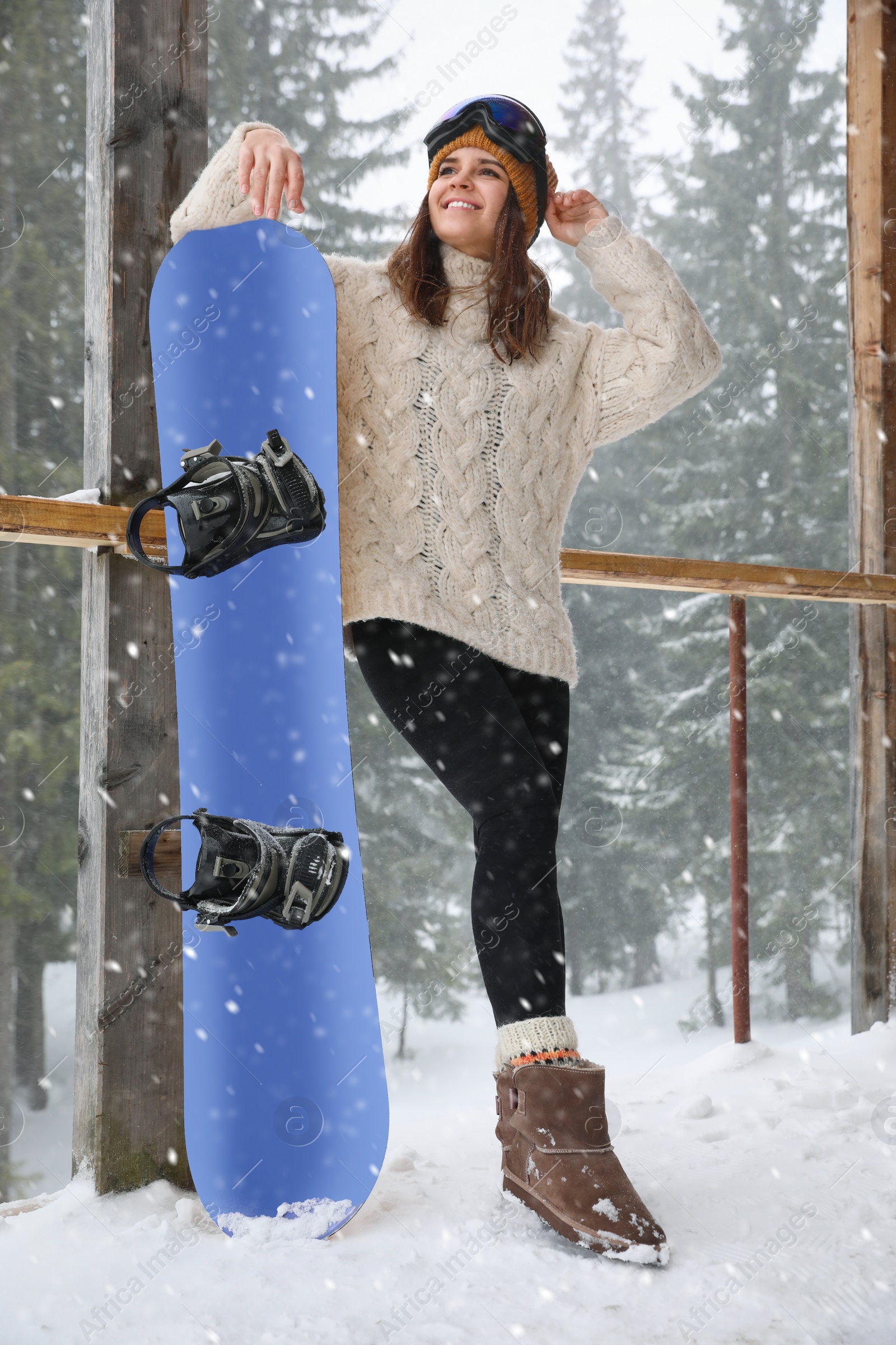 Photo of Young woman with snowboard wearing winter sport clothes and goggles outdoors