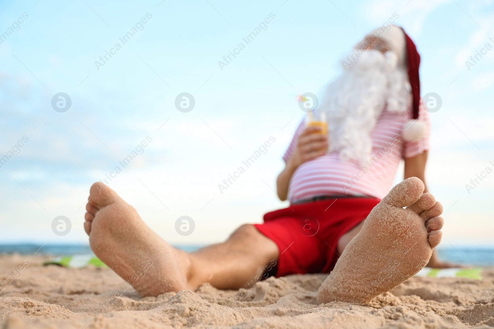 Photo of Santa Claus with cocktail relaxing on beach, space for text. Christmas vacation