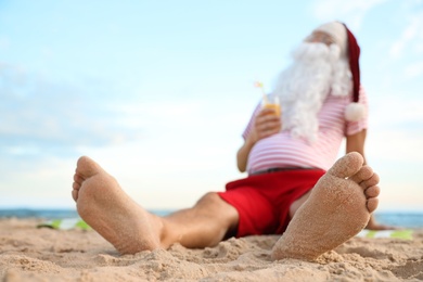 Photo of Santa Claus with cocktail relaxing on beach, space for text. Christmas vacation