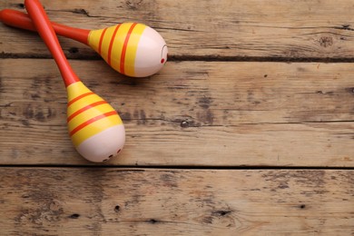 Colorful maracas on wooden table, top view with space for text