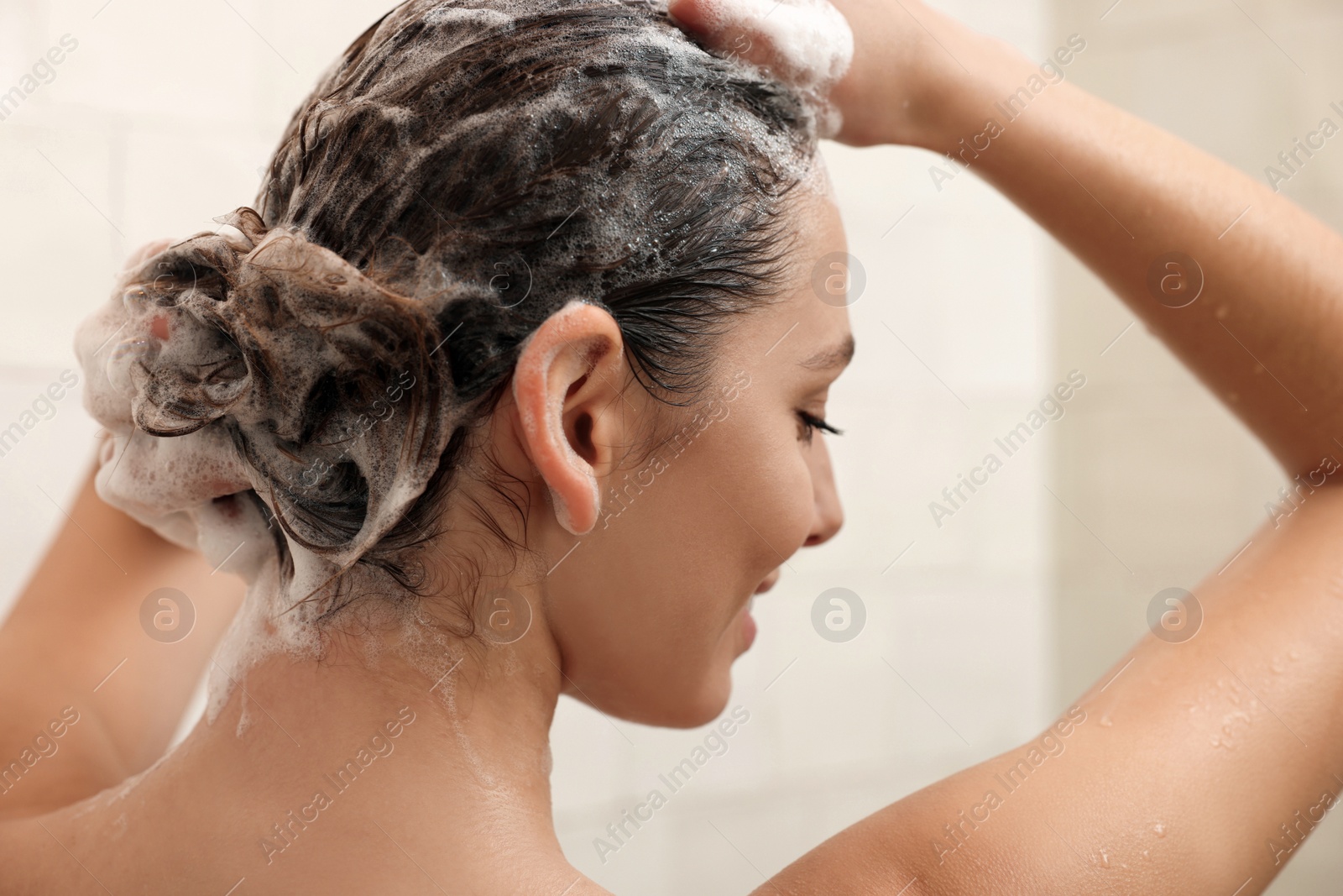 Photo of Young woman washing hair while taking shower at home