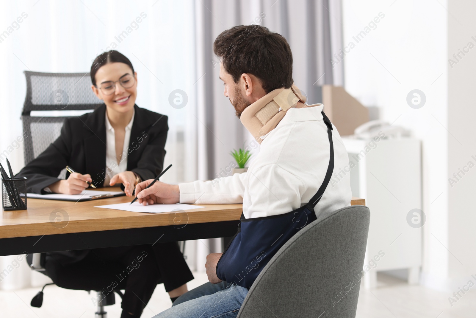 Photo of Injured man signing document in lawyer's office, selective focus