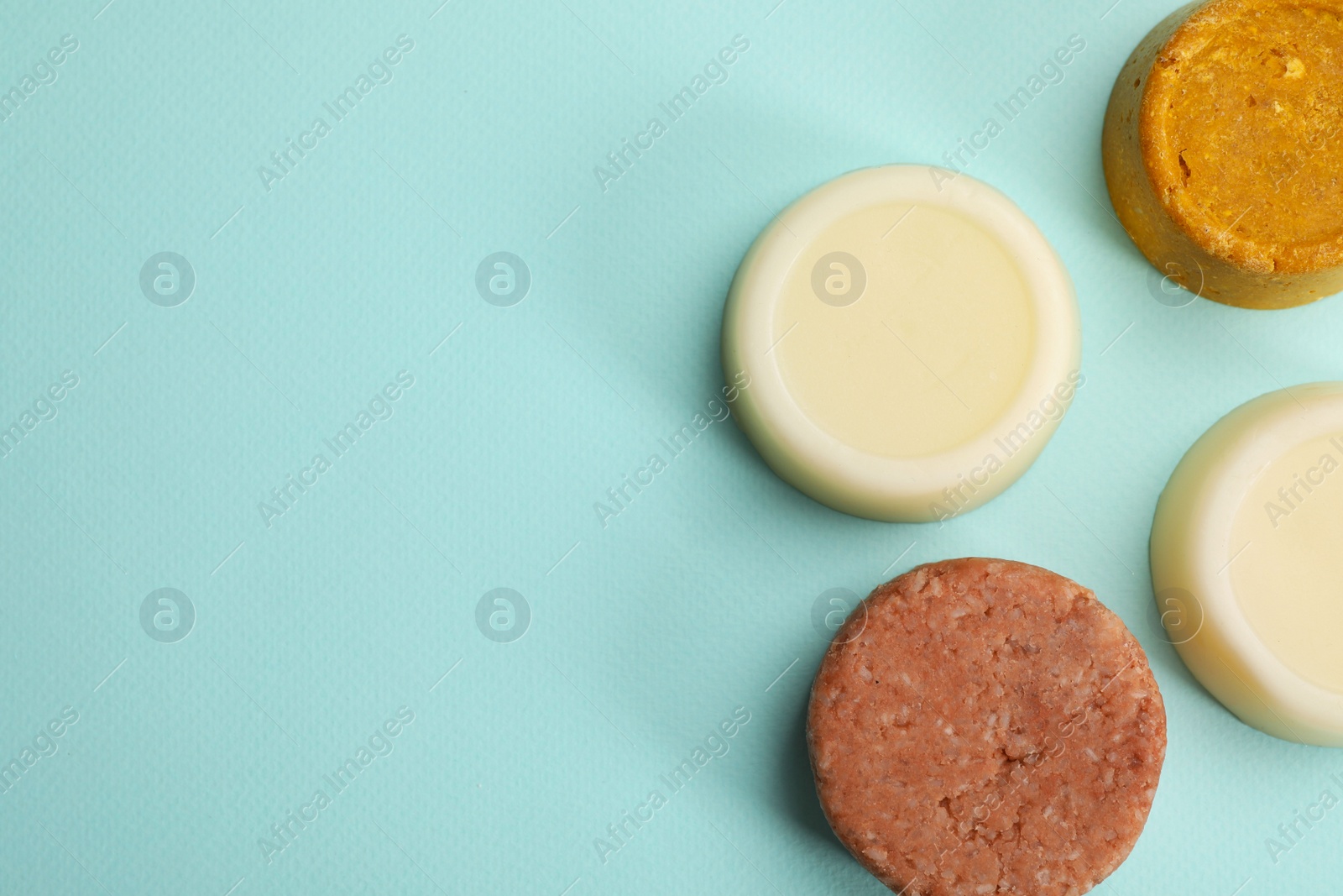 Photo of Group of solid shampoo bars on turquoise background, flat lay. Space for text