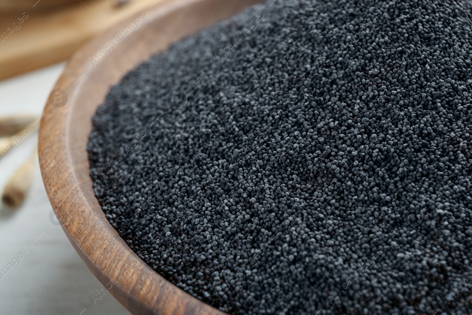 Photo of Poppy seeds in wooden bowl, closeup view