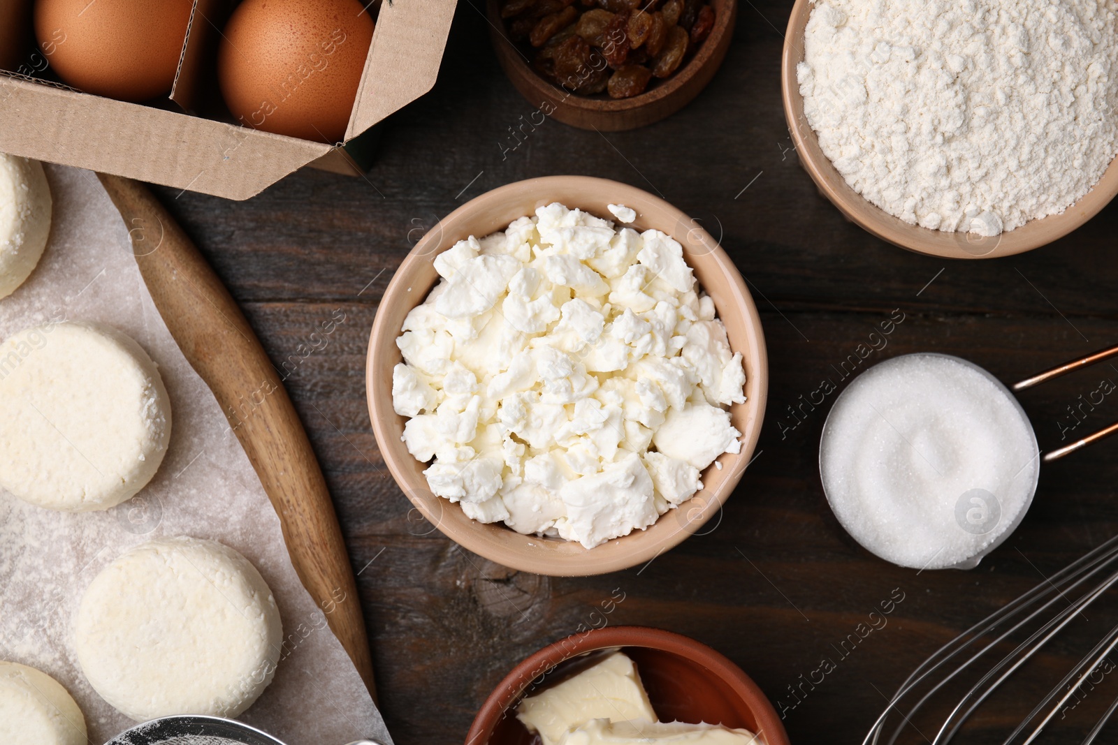 Photo of Uncooked cottage cheese pancakes and different ingredients on wooden table, flat lay