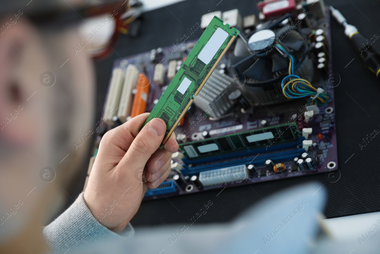 Photo of Male technician repairing motherboard at table, closeup