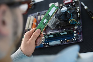 Male technician repairing motherboard at table, closeup