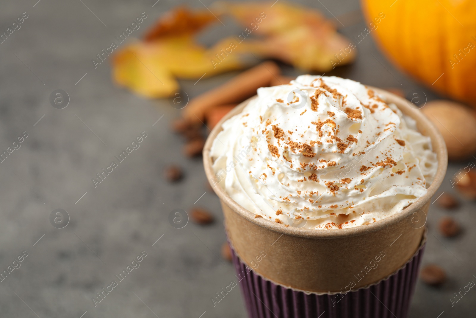 Photo of Paper cup with tasty pumpkin spice latte on grey table, closeup