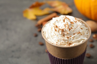 Paper cup with tasty pumpkin spice latte on grey table, closeup