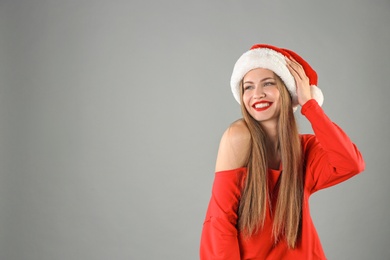 Photo of Young beautiful woman in Santa hat on grey background. Christmas celebration