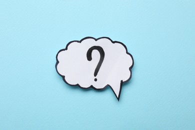 Photo of Paper speech bubble with question mark on light blue background, top view
