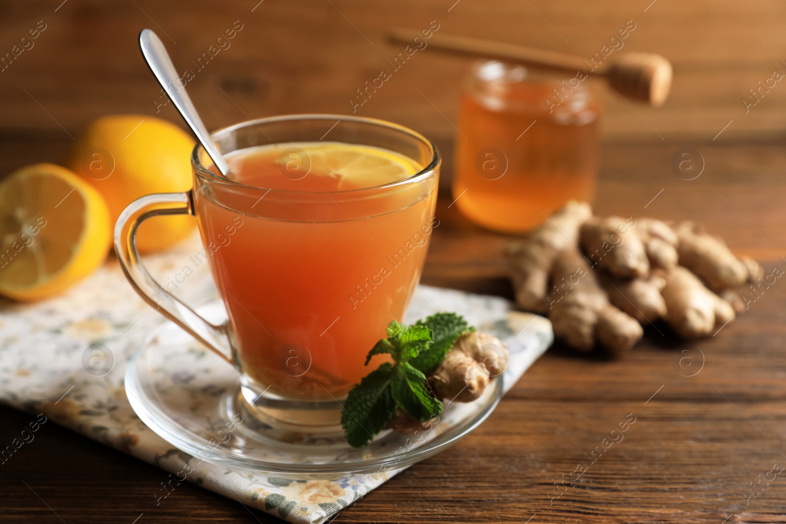 Photo of Cup of delicious ginger tea and ingredients on wooden table, space for text
