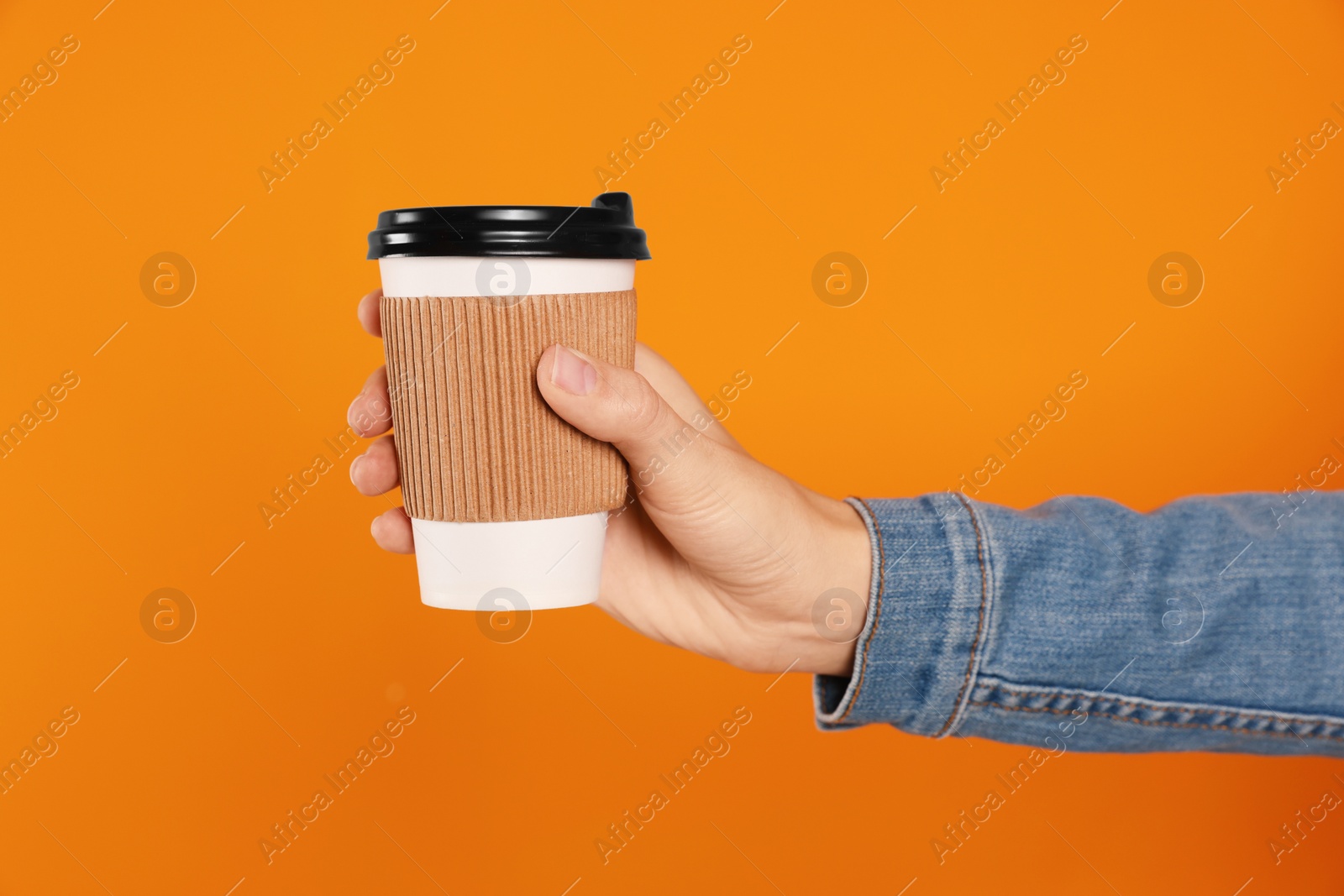 Photo of Woman holding takeaway cup with drink on orange background, closeup. Coffee to go