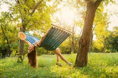 Photo of Young woman swinging in comfortable hammock at green garden