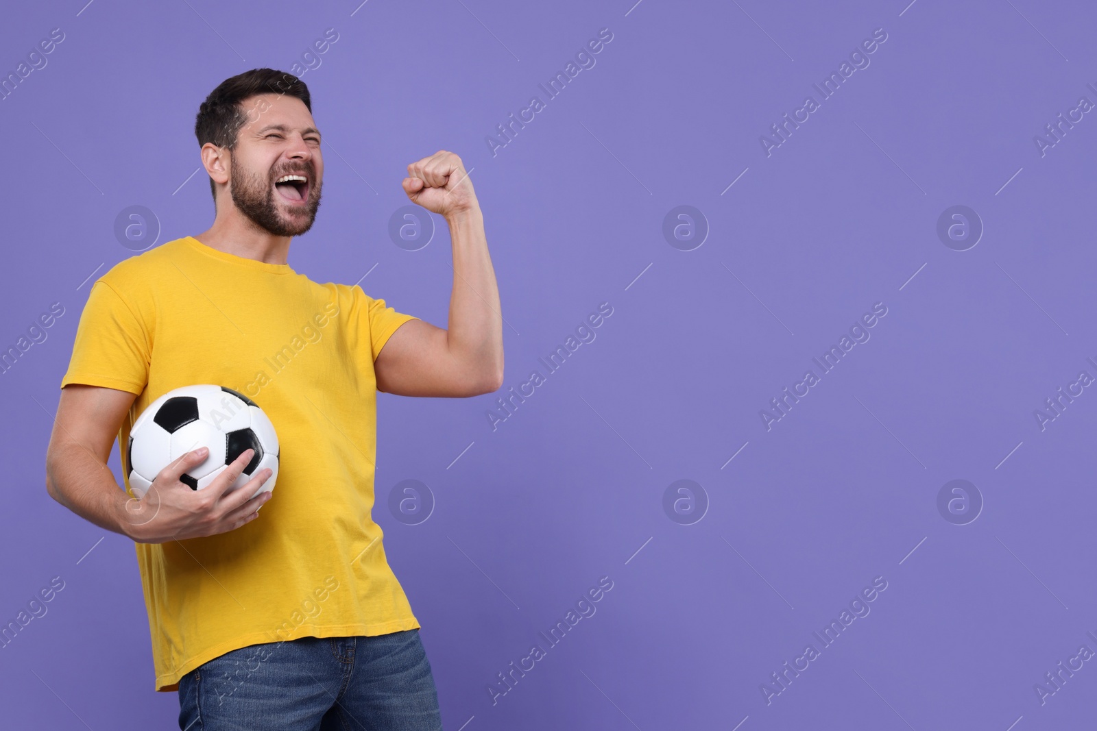 Photo of Emotional sports fan with ball celebrating on purple background. Space for text