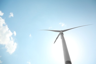 Modern wind turbine against blue sky, low angle view. Energy efficiency