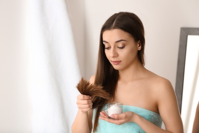 Photo of Woman holding glass bowl with hair mask on blurred background. Split ends